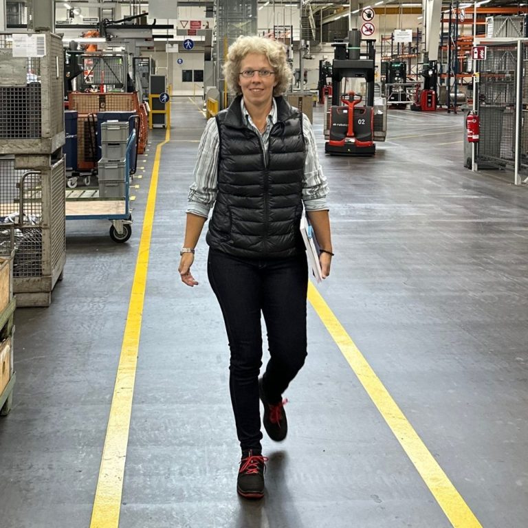 Victoria Weyers von Weyers Safety Skills, Trainerin der Führungskräfte, geht durch eine große Produktionshalle. 